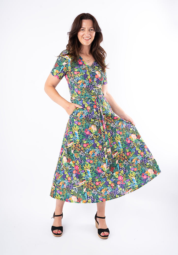 Woman wearing a colourful floral midi dress with hand in pocket