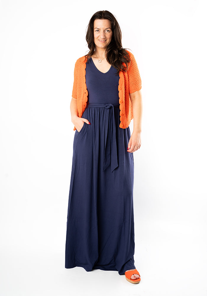 Woman wearing a navy maxi dress with an orange cardigan