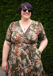Woman wearing a floral midaxi dress with a green floral and tiger background