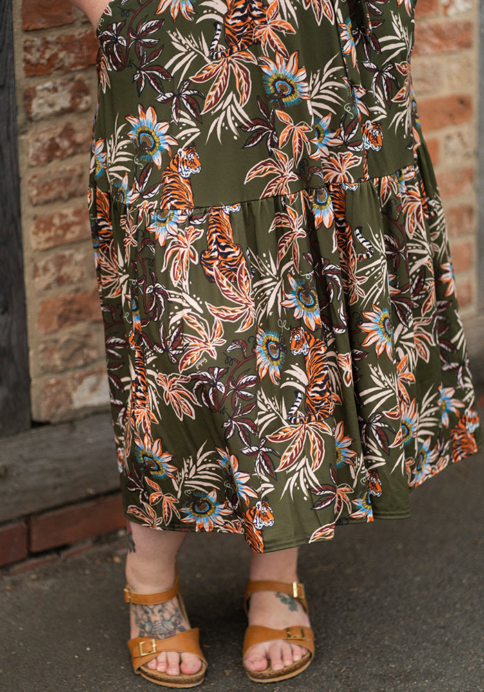 Person wearing a long, patterned tiger print midaxi dress with a brick wall background