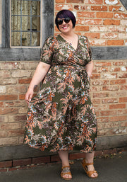 Woman wearing a floral tiger midaxi dress standing against a brick wall.