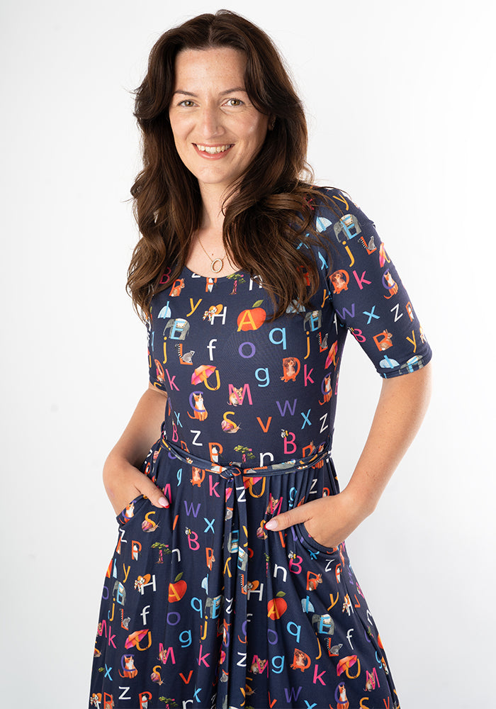 Woman wearing a navy dress with colorful alphabet phonics pattern