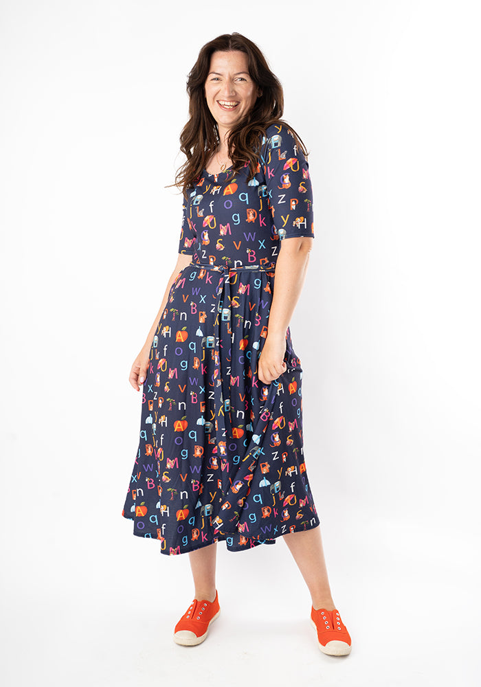 Woman wearing a navy midi dress with colourful alphabet phonics pattern