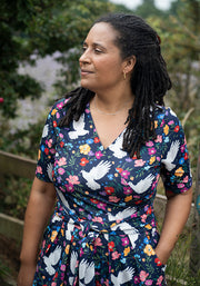 Woman wearing a dress with floral and dove pattern outdoors