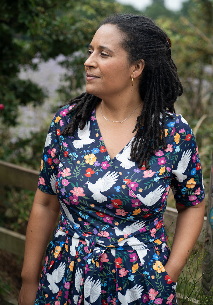 Woman wearing a dress with floral and dove pattern outdoors