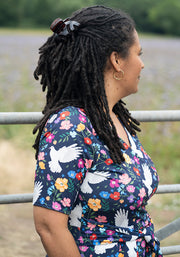 Woman wearing a floral dress with white bird designs.