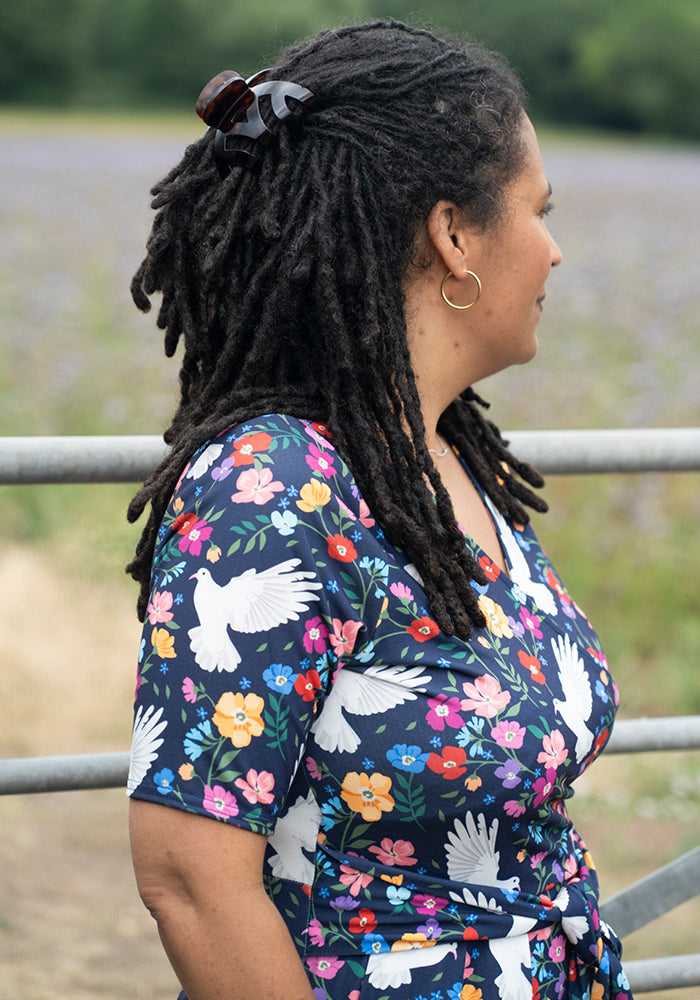 Woman wearing a floral dress with white bird designs.