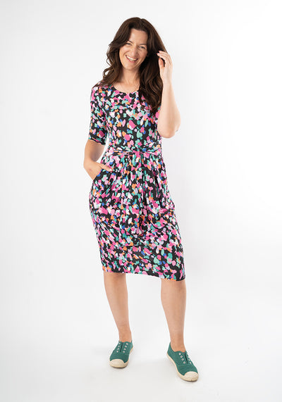 Woman wearing a colourful animal print dress with hand in pocket