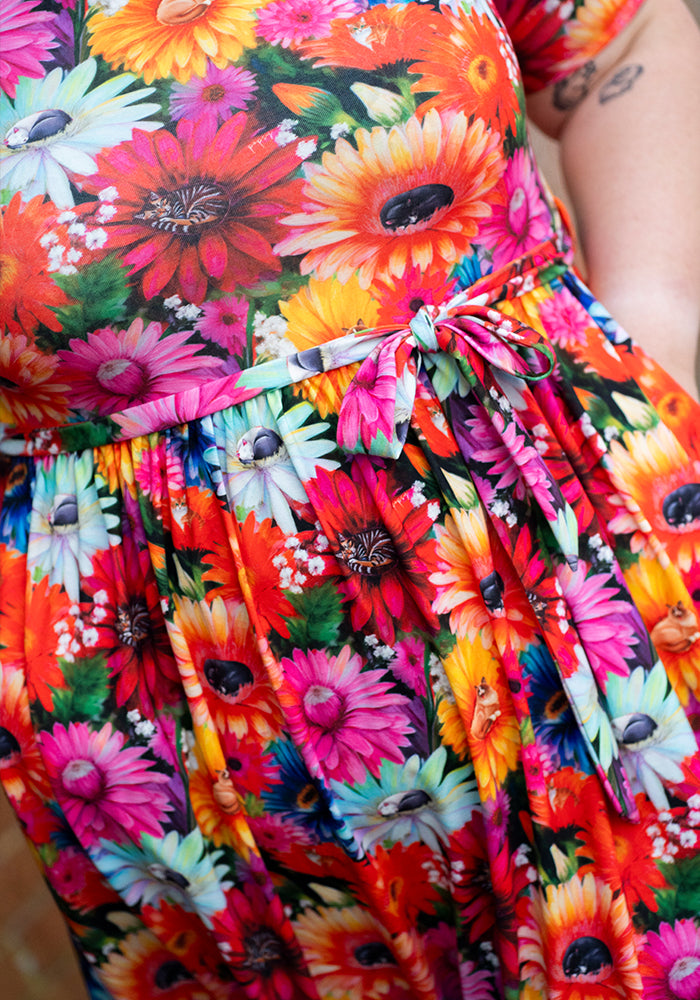 Close-up of a colourful floral and cat print dress with hand in pocket