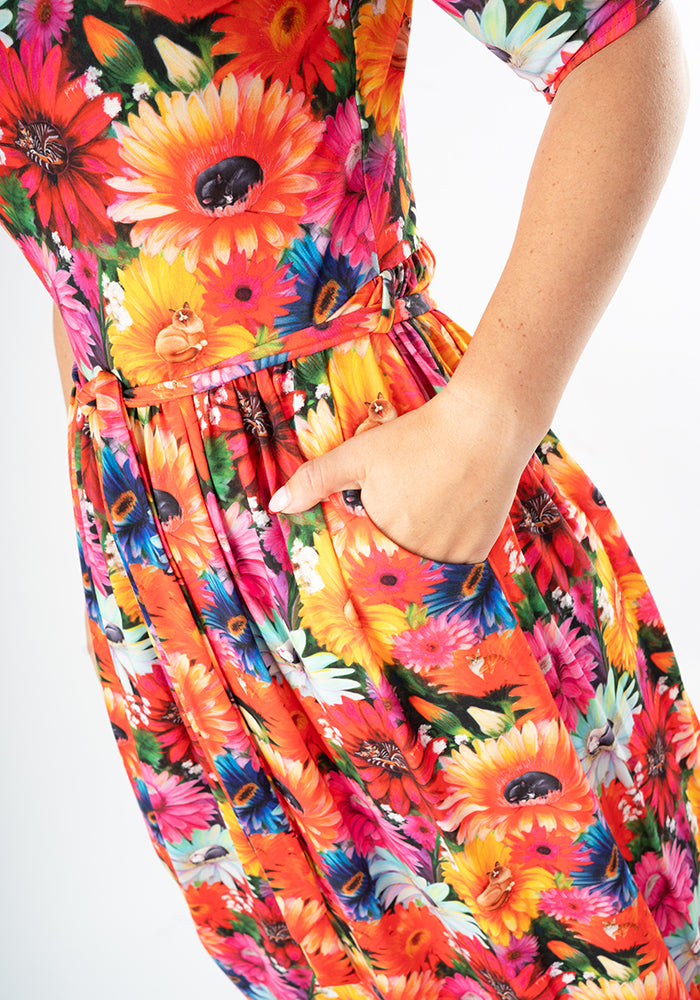 Colorful floral and cat print midi dress with a close-up of a hand in pocket