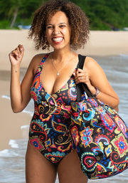 Woman in a colourful paisley swimsuit and matching bag on a beach