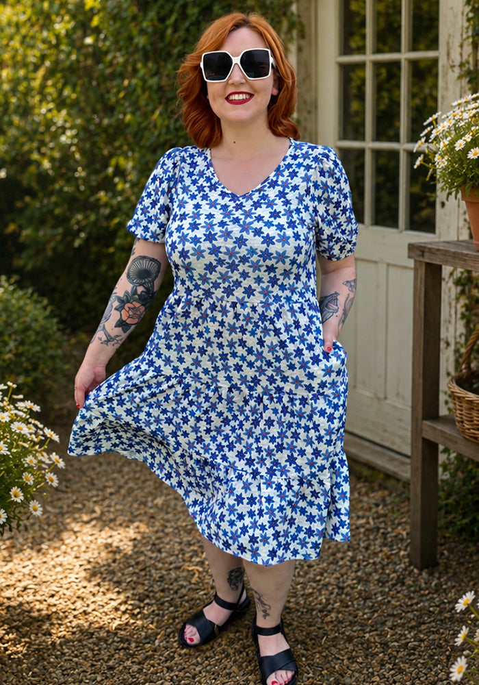Front view of Reyna Blue Flowers Print Tiered Dress, a pretty volre fabric dress with a blue floral print on a cream ground.