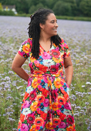 Woman in a colourful floral and cat dress standing in a field of flowers