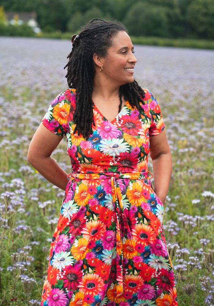 Woman in a colourful floral and cat dress standing in a field of flowers