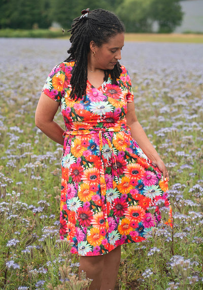 Woman in a colourful floral and cat dress standing in a field of flowers