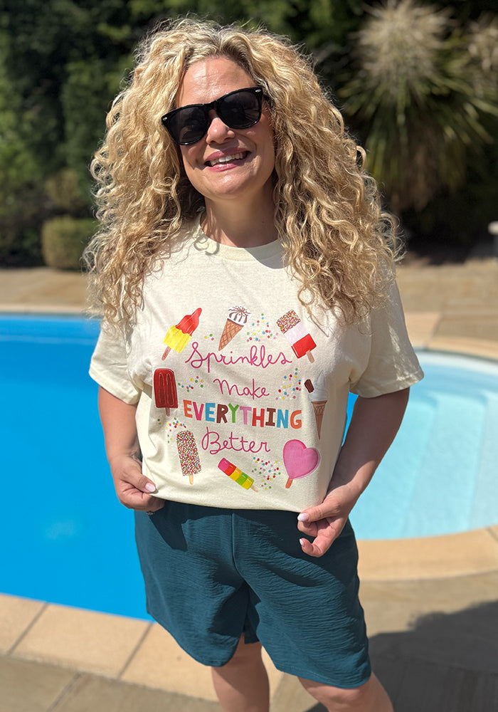 Front view of Sprinkles Graphic Print T-Shirt (Cream), a cream tee with "Sprinkles Make Everything Better" positive slogan.